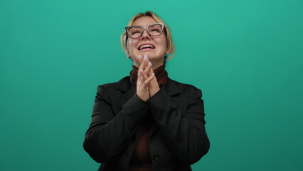 Woman expressing frustration and anxiety over a green background wall, hands on face, blonde hair,...