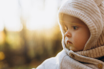 Portrait of happy cute baby boy in soft evening light in autumn woods. Childhood. Adorable child in cozy warm sweaters in fall park, space for text