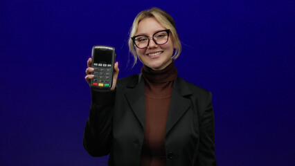 Woman displaying payment terminal over isolated blue background, indicating ease of use and modern...
