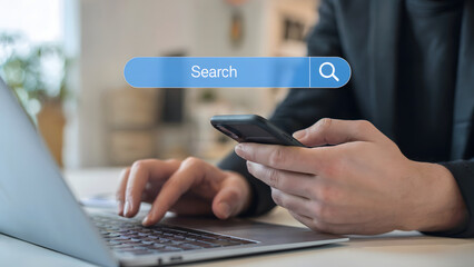 Person using a laptop and smartphone for online search, highlighting connectivity, technology, and modern communication in a business setting, reflecting convenience and efficiency.