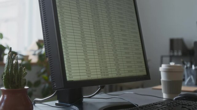 Close-up view of spreadsheet on screen of office computer placed on grey work desk of call centre operator