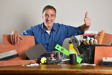 Tiler with ok gesture showing tools on wooden table
