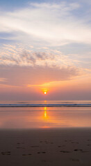 Naklejka premium Serene Coastal Sunrise with a Golden Sun Reflected on Wet Sand and Gentle Ocean Waves, Featuring Clear Footprints