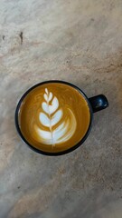 cup of coffee. A meticulously crafted latte art design, resembling a delicate leaf, beautifully...