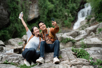Hiking and Selfies. Friends capture a joyful moment on a hiking trip near a waterfall.