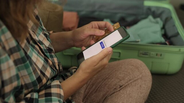 Online payment for last minute tour. Woman booking a hotel using credit card and smartphone