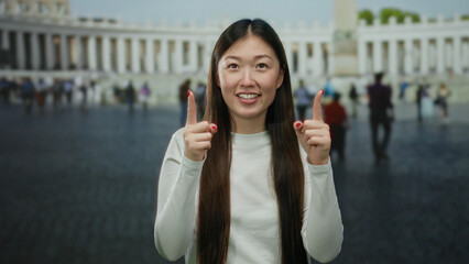 Woman smiling in the vatican's st. peter's square points upward, capturing a joyful moment amid a...