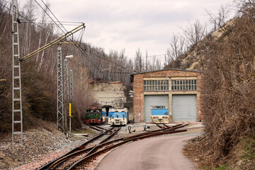 Vor der Einfahrt in einen Bergwerkstollen steht eine Lok.
