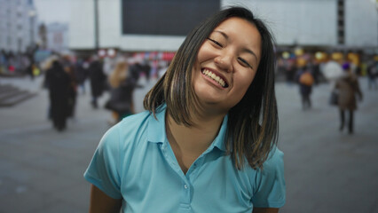 Woman smiling on busy urban street showcases joy and diversity in city life with people and motion in the background.