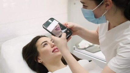 A cosmetologist takes a photo of a young woman's face on her phone after performing cosmetology services. The concept of distance learning and cosmetology services.