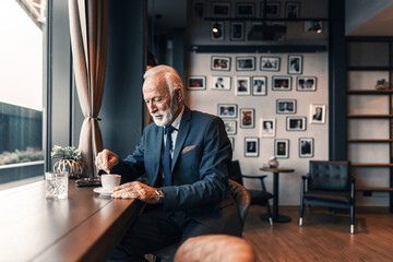 Elegant Senior Man Enjoying Coffee in a Modern Café