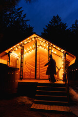 Glamping from tent houses in the forest in the dark. silhouette of a woman