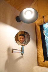 Lamp and round mirror in the bathroom in the tent house in the glamping.