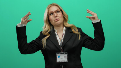 Woman wearing glasses gestures animatedly against a green background in a business suit with id...