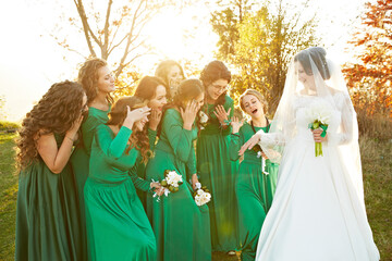 A bride and her bridesmaids are posing for a picture. The bride is wearing a white dress and a...