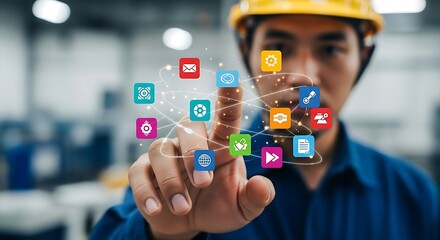 Asian engineer in yellow hardhat interacts with digital interface in modern technology factory setting.