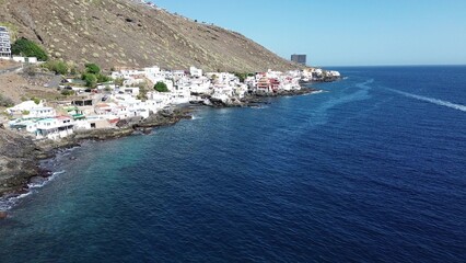 Coastal town on Tenerife with crashing waves and dense white architecture, aerial view
