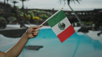Mexican flag held by caucasian man stands against a sunny resort with palm trees and a pool in an...