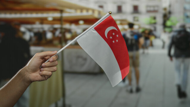 Man holding singaporean flag in an outdoor street market setting depicting national pride and cultural diversity.