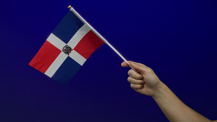 Man holding dominican republic flag against blue wall showing patriotism and celebration in an...