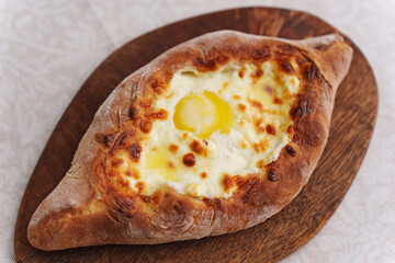 Delicious Adjarian khachapuri with cheese and egg served on wooden board