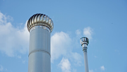 Vibrant metal chimneys against a clear blue sky on a rooftop terrace showcasing modern...