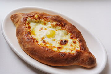 Delicious Adjarian khachapuri with melted cheese and egg on a plate