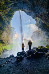 Majestic view from behind Kvernufoss waterfall in Iceland with visitors enjoying the spray