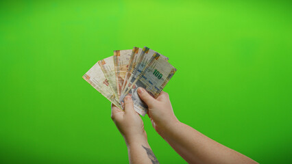 Woman holding peruvian soles against a vibrant green background, symbolizing business and financial...