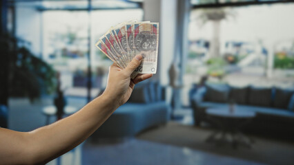 Man holding polish zloty banknotes indoors at a hotel reception, highlighting financial...