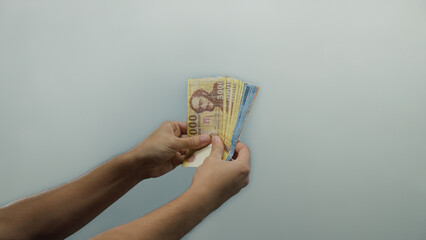 Man holding hungarian forint banknotes over isolated white background wall showcasing currency...