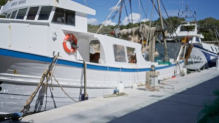 Fototapeta premium Blurred boats docked at picturesque cala figuera port in mallorca, showcasing a vibrant scene with focus on bokeh effect and serene coastal surroundings.