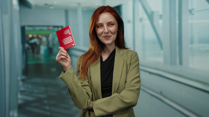 Woman holding swiss passport in airport terminal with a smile, standing in professional attire,...
