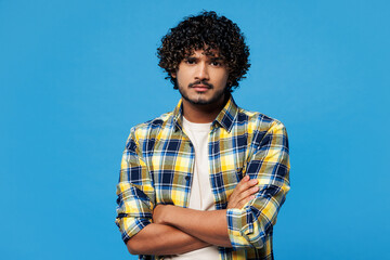 Young sad mad frowning Indian man he wearing yellow checkered shirt casual clothes hold hands...