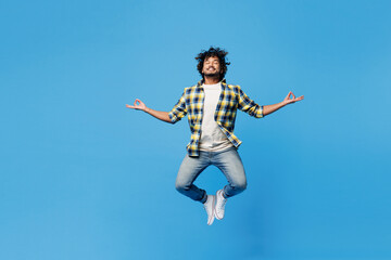 Full body young happy Indian man wear yellow checkered shirt casual clothes jump high hold spread...