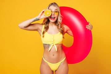 Young surprised beautiful sexy woman wear bikini swimsuit rest near hotel pool hold in hand half of...