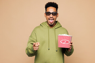 Young man of African American ethnicity he wear green hoodie casual clothes 3d glasses watch movie...