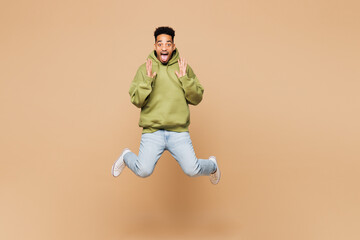 Full body young shocked surprised happy man of African American ethnicity wears green hoodie casual...