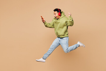 Full body young winner man of African American ethnicity wears green hoodie casual clothes jump...