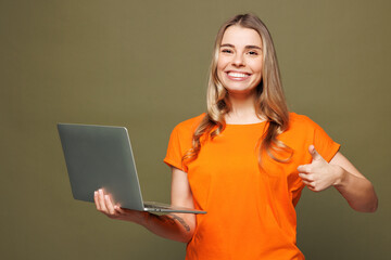 Young smiling Caucasian IT woman she wears orange t-shirt casual clothes hold use work on laptop pc...