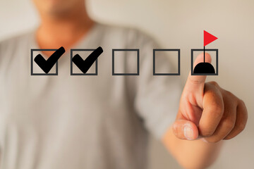  A person's finger points to a final goal flag on a virtual checklist. Concept for project...