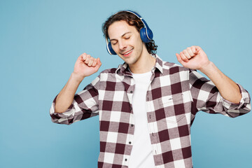 Young happy man he wear purple checkered shirt casual clothes listen to music in headphones raise...