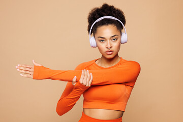 Young strong fitness trainer instructor sporty woman sportswoman wear headphones orange clothes...