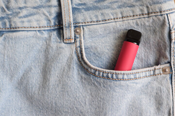 One red electronic cigarette in the pocket of jeans. Vape with nicotine.
