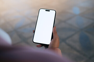 A close-up of a woman using a smartphone with a blank white screen at night. Technology, communication, and digital interaction in a modern urban setting.