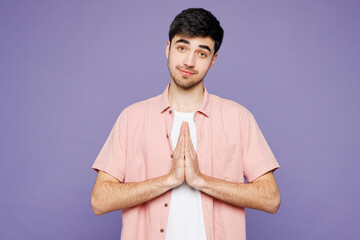 Young man he wears pink shirt t-shirt casual clothes hold hands folded in prayer gesture, begging...