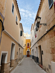 Perspective view of a typical town street in ciutadella menorca with winding cobbled road old traditional painted houses and street lamps