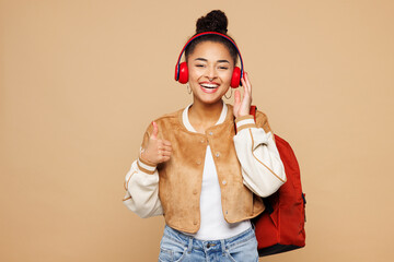 Young smart girl student wear casual clothes backpack bag hold books listen to music in headphones...