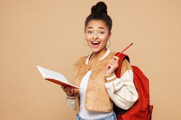 Young surprised shocked girl student wears casual clothes backpack bag hold book write down in...