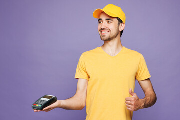 Young delivery guy employee man in yellow cap t-shirt uniform workwear work as dealer courier hold...